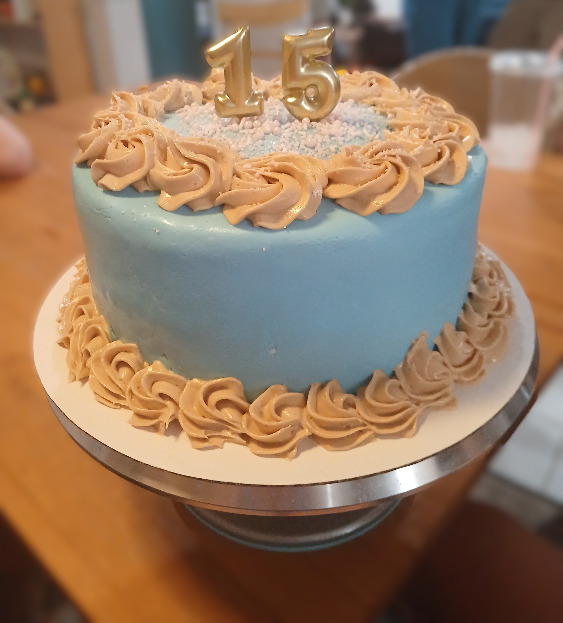 Blue cake with gold rosettes and a number 15 topper